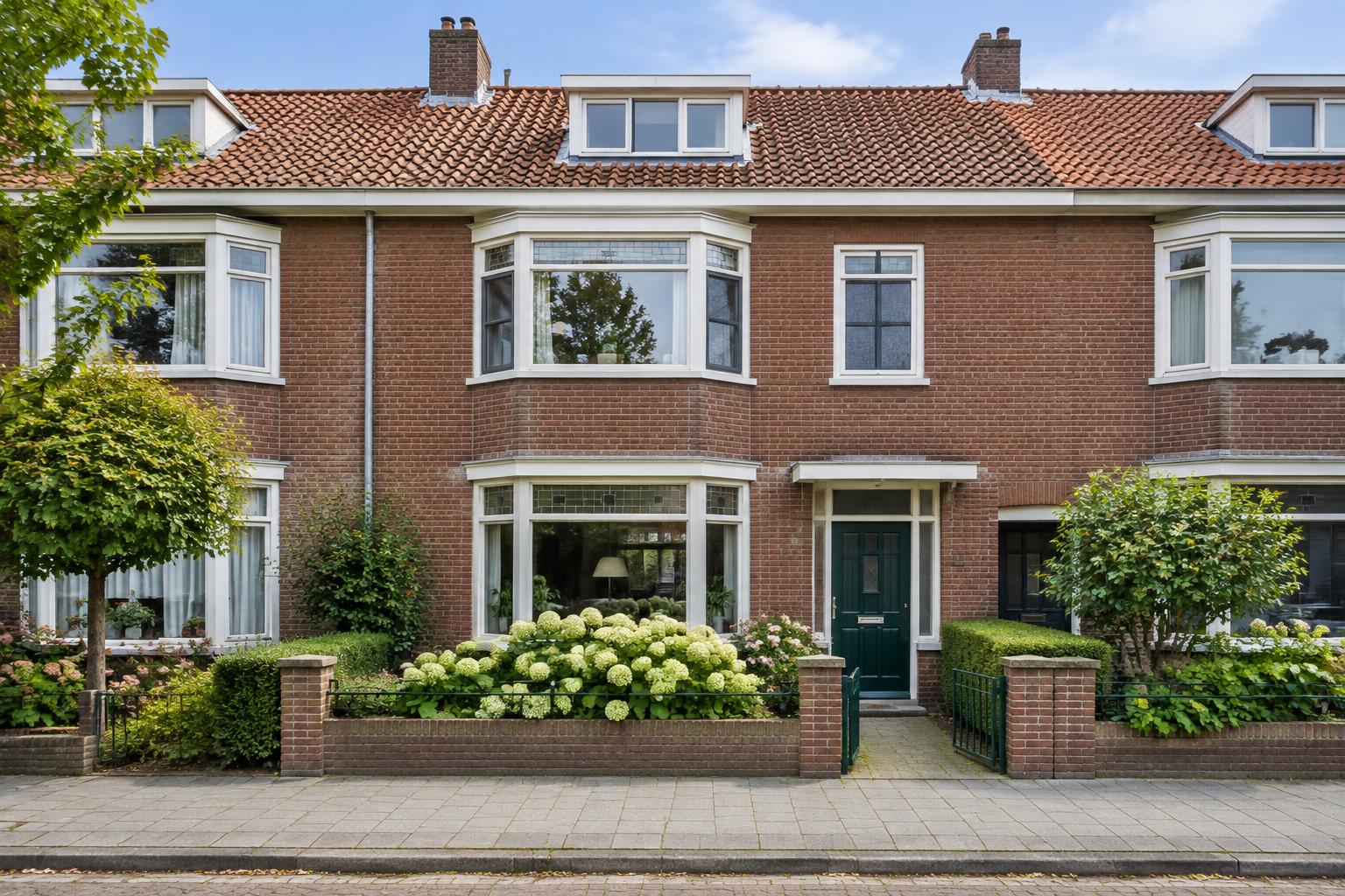 Bakstenen jaren-dertigwoning met erker en groene voordeur